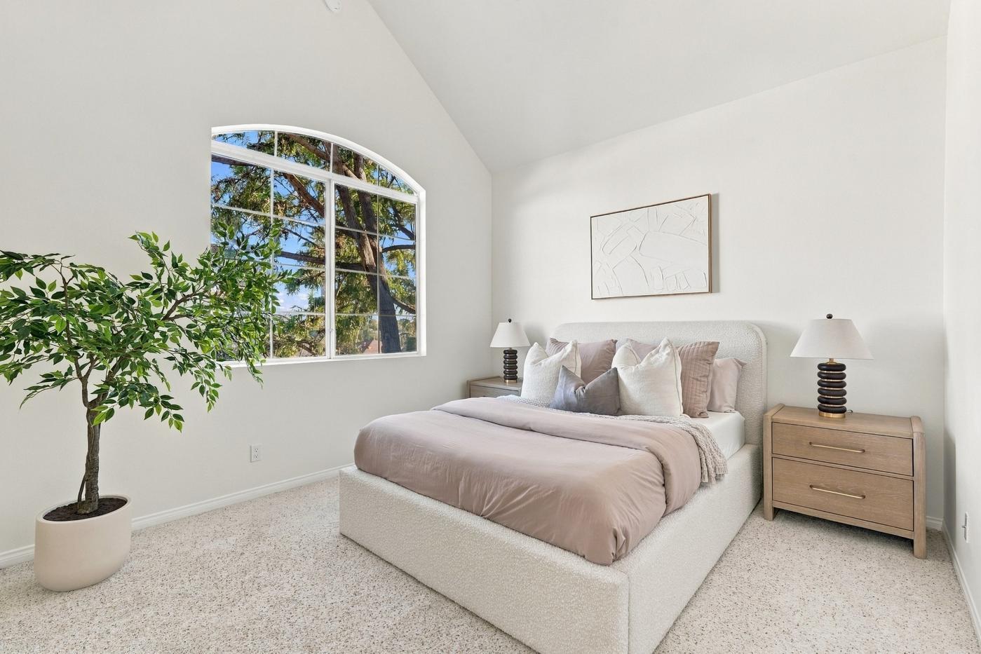 The same bedroom staged with a bed, artwork and a plant